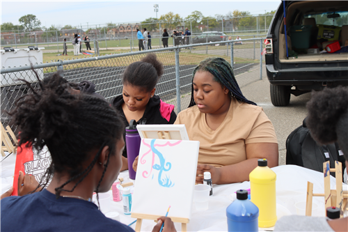 3 girls painting with a truck in the background